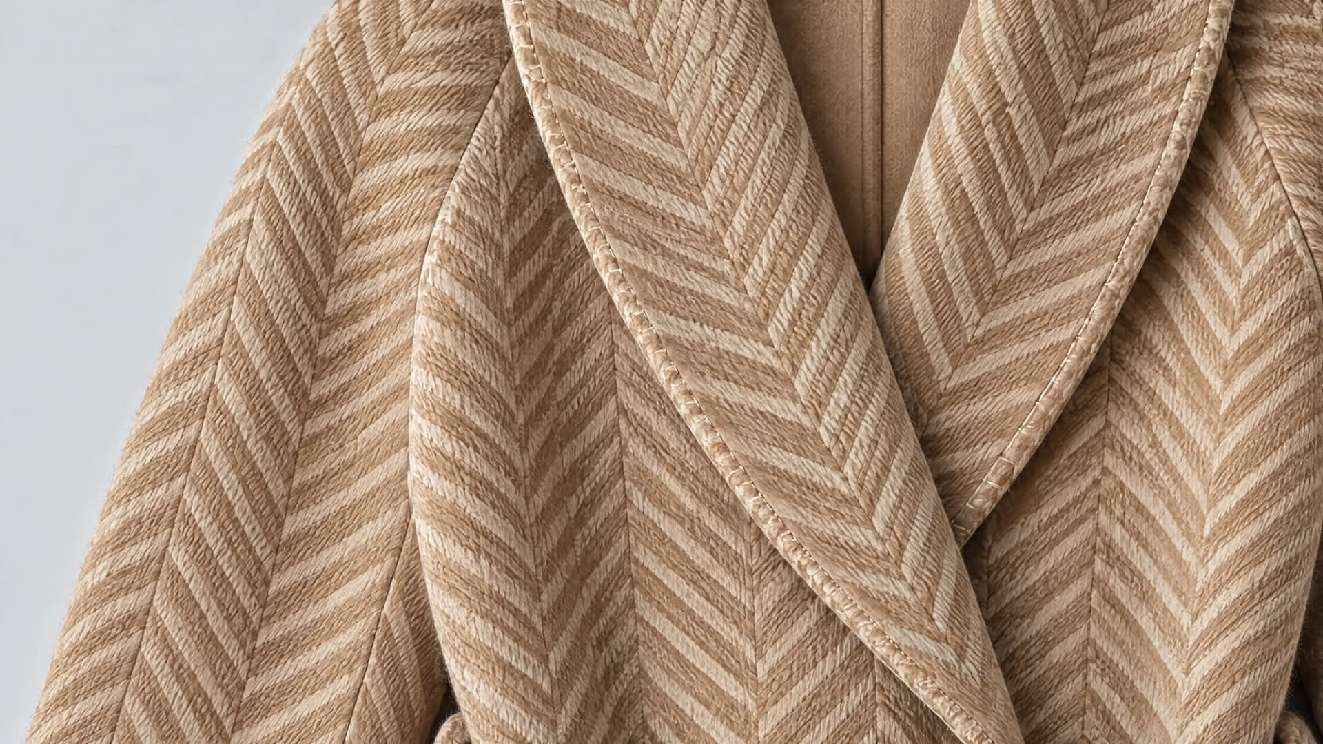 Close-up of the herringbone weave and shawl collar of a camel wool coat